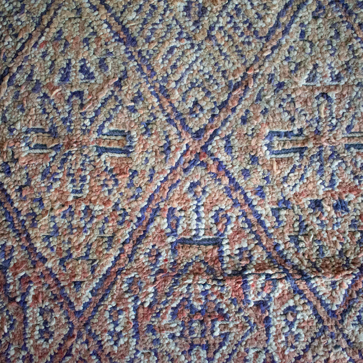 Close-up view of a vintage Moroccan area rug showcasing its textured weave and geometric pattern in multiple colors.