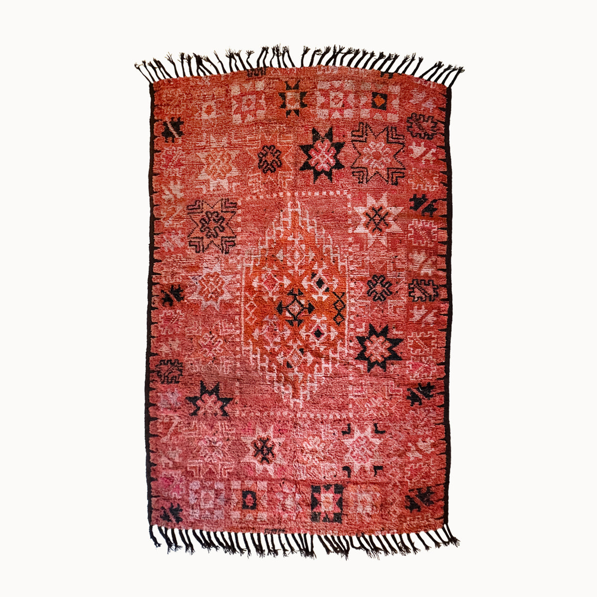 Red patterned rug with black and white designs on a white background