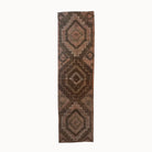Long rectangular brown rug with geometric pattern on a white background