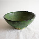 A dark green Tamegroute ceramic bowl with a rough, textured finish on a light background.